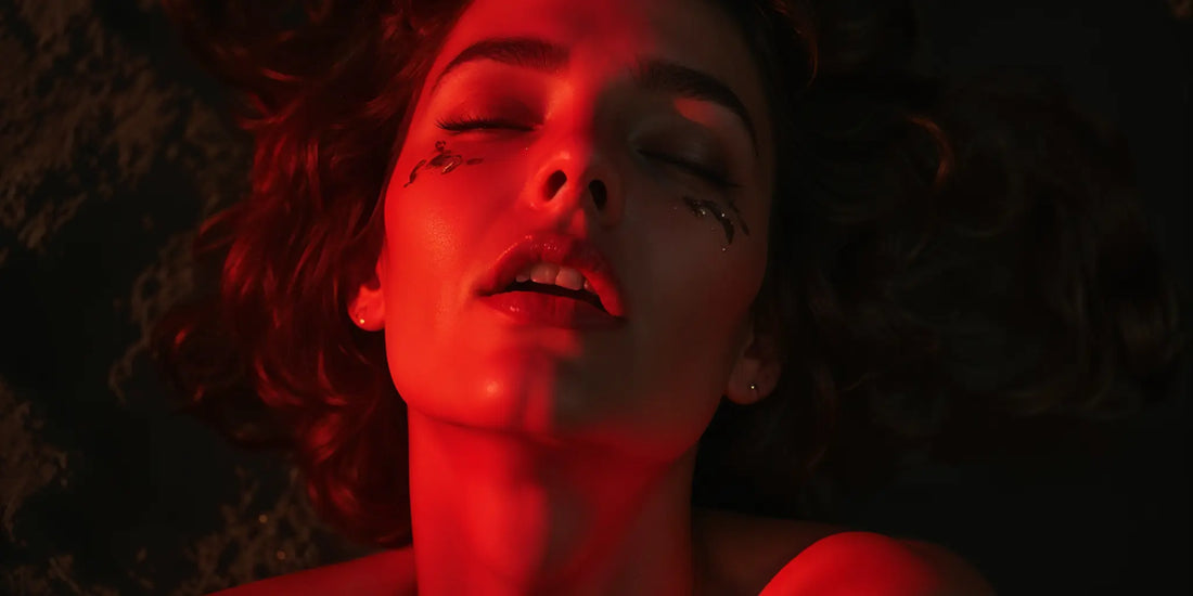 Women achieving clitoral orgasm with red light on her face and open mouth.